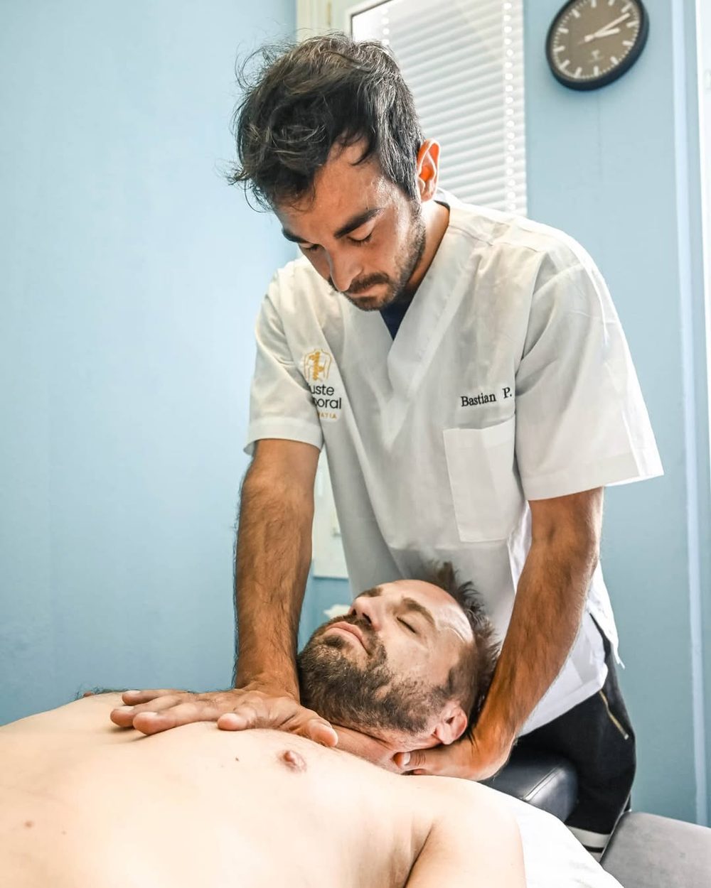 Bastian Parada tratando la zona cervical de un paciente en camilla